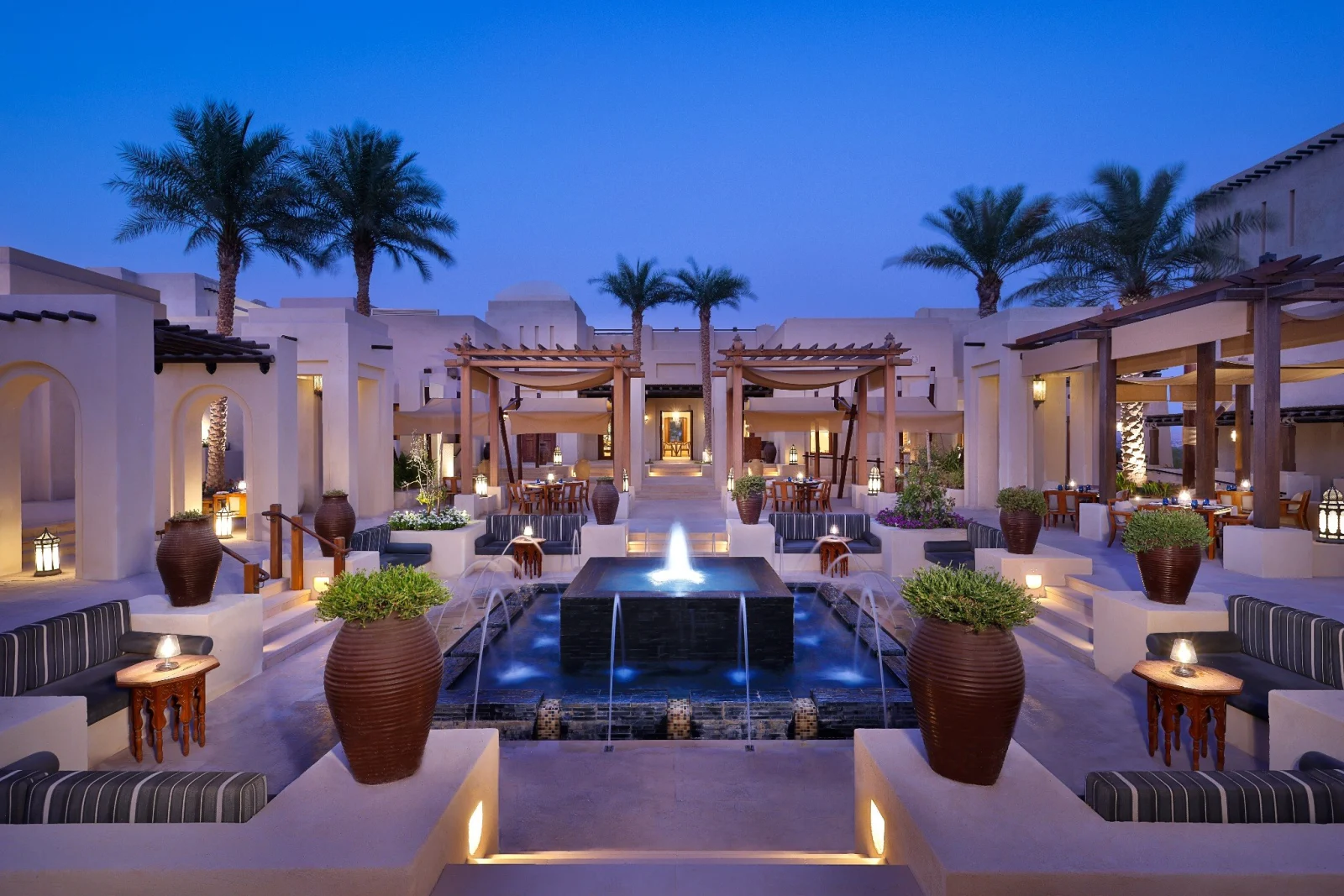 Al Wathba resort courtyard with traditional architecture and a central fountain at dusk